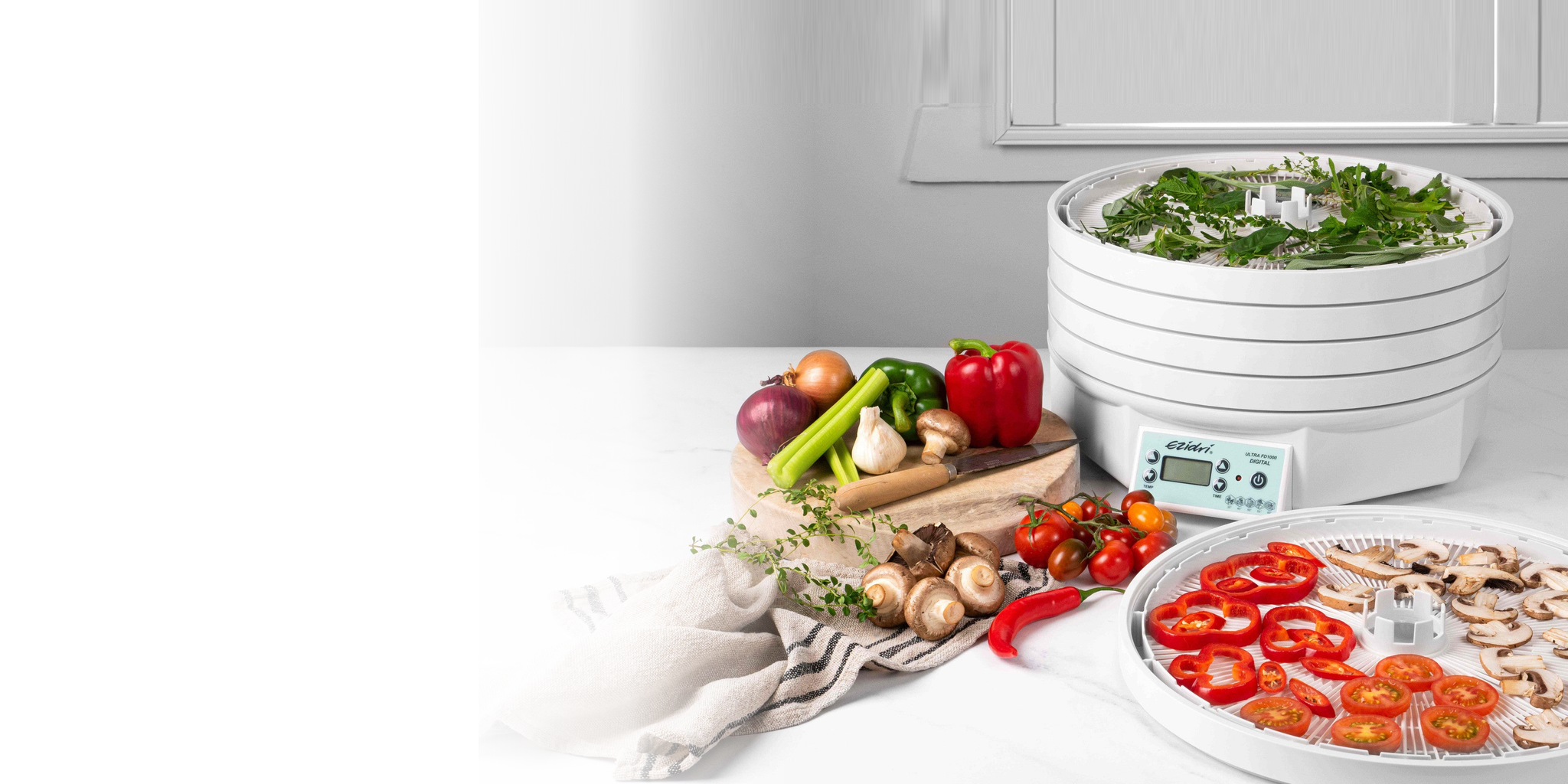 Ezidri FD1000 dehydrator with fresh herbs, vegetables and dried food on trays in a bright white kitchen